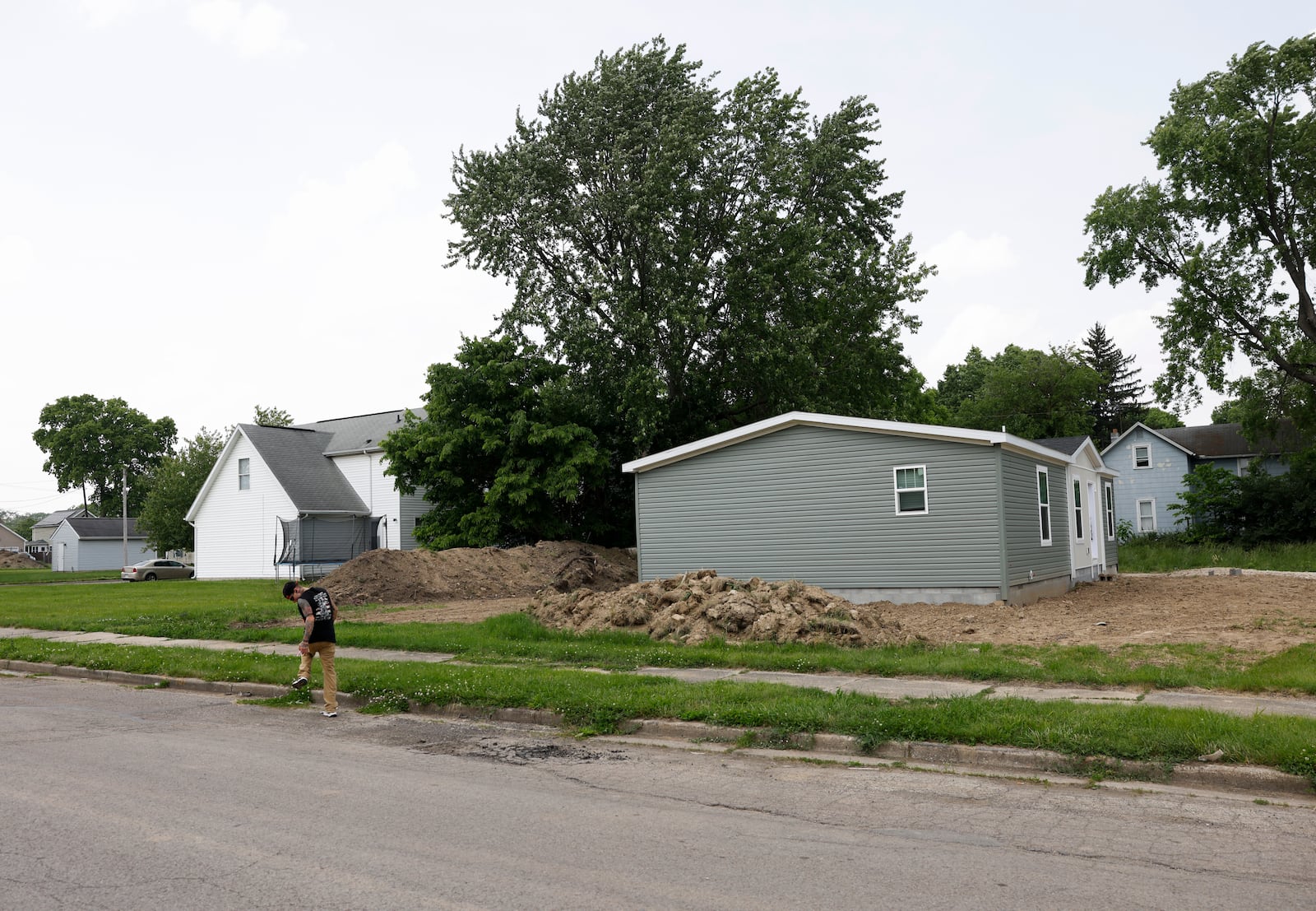 A man walks down East Liberty Street on Wednesday, June 4, 2025, in Springfield. Four new homes are being built here by Clark County Land Bank. JOSEPH COOKE/STAFF