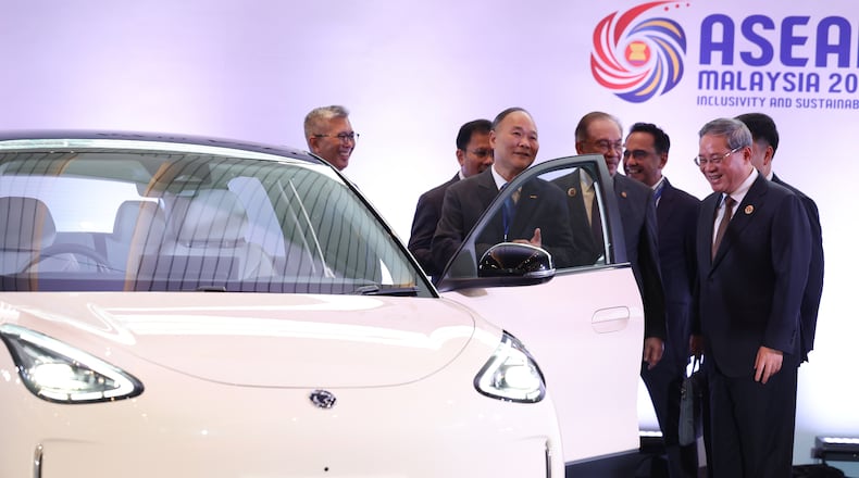 Chinese Premier Li Qiang, right, reacts as he, along with Malaysian Prime Minister Anwar Ibrahim, center, inspects a car produced by Malaysia's national automaker, Proton, in which China's Zhejiang Geely Holding Group holds a 49.9% stake, ahead of the signing ceremony for the ASEAN–China Free Trade Area 3.0 Upgrade and the ASEAN–China summit, held as part of the ASEAN summit in Kuala Lumpur, Malaysia Tuesday, Oct. 28, 2025. (Chalinee Thirasupa/Pool Photo via AP)