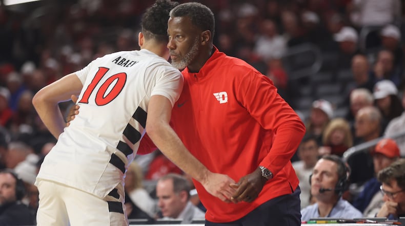 Dayton's Anthony Grant gets a hug from Cincinnati's Shon Abaev, who UD recruited, on Tuesday, Nov. 11, 2025, at Fifth Third Arena in Cincinnati. David Jablonski/Staff