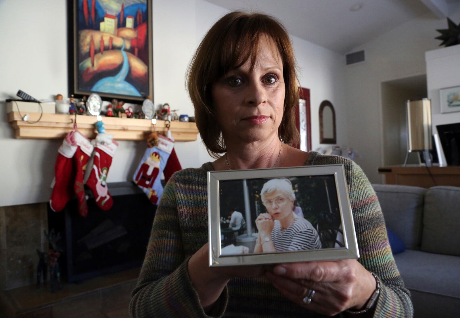 FILE - Birte Pfleger holds a photo, Dec. 14, 2017, in Long Beach Calif. of her mother, Gisela Pfleger, she took in 1994, two days before her mother was killed. (AP Photo/Reed Saxon)