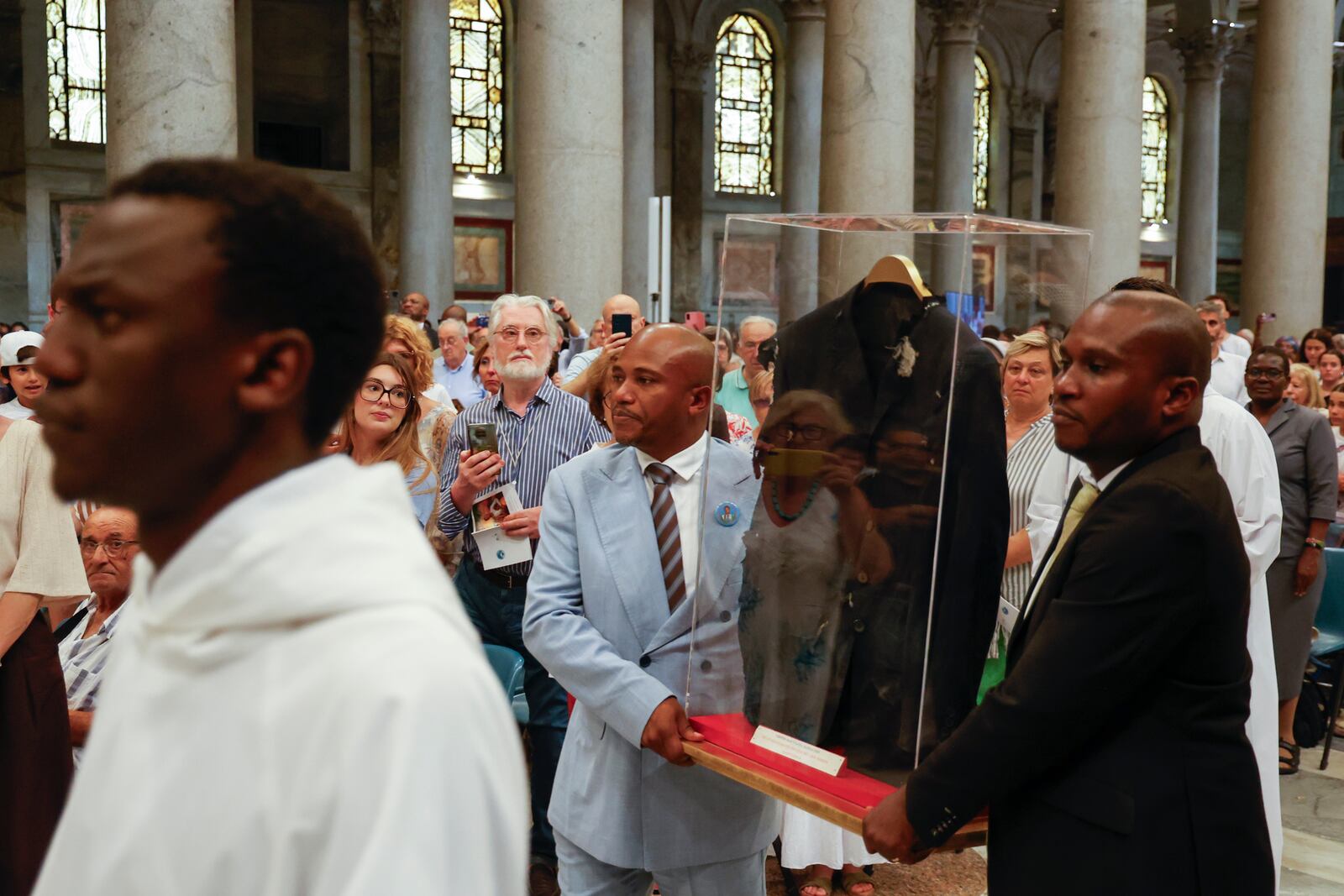 The jacket that Floribert Bwana Chui Bin Kositi was wearing at the time of his assassination is carried as a relic by his brothers Jean-Claude, left, and Trésor, at the start of a ceremony for his beatification in St. Paul Outside the Walls' Basilica, in Rome, Sunday, June 15, 2025. (AP Photo/Riccardo De Luca)
