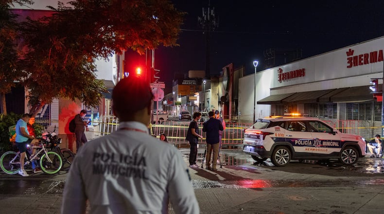 Policeman stands near a convenience store destroyed by a fire in Hermosillo, Sonora state, Mexico, Saturday, Nov. 1, 2025. (AP Photo/Abraham Tellez)