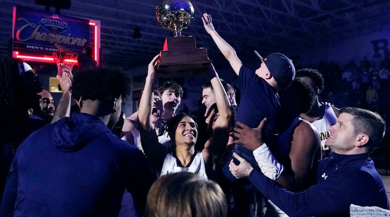Merrimack guard Javon Bennett holds up the trophy while celebrating after defeating Fairleigh Dickinson to win the Northeast Conference men's NCAA college basketball championship, Tuesday, March 7, 2023, in North Andover, Mass. (AP Photo/Charles Krupa)