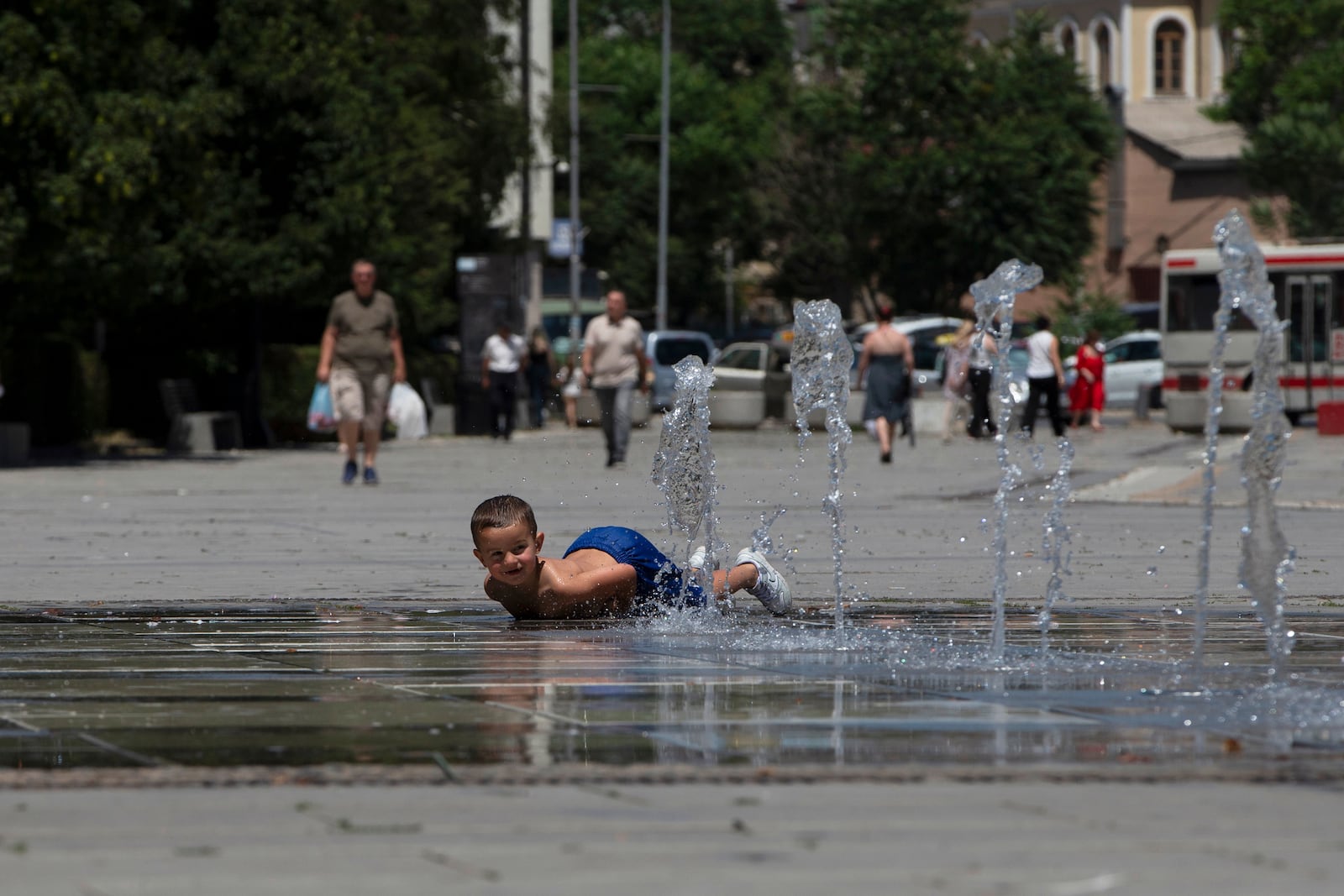 A boy plays in a fountain during hot weather in Kosovo's capital Pristina on Thursday, July 3, 2025. (AP Photo/Visar Kryeziu)