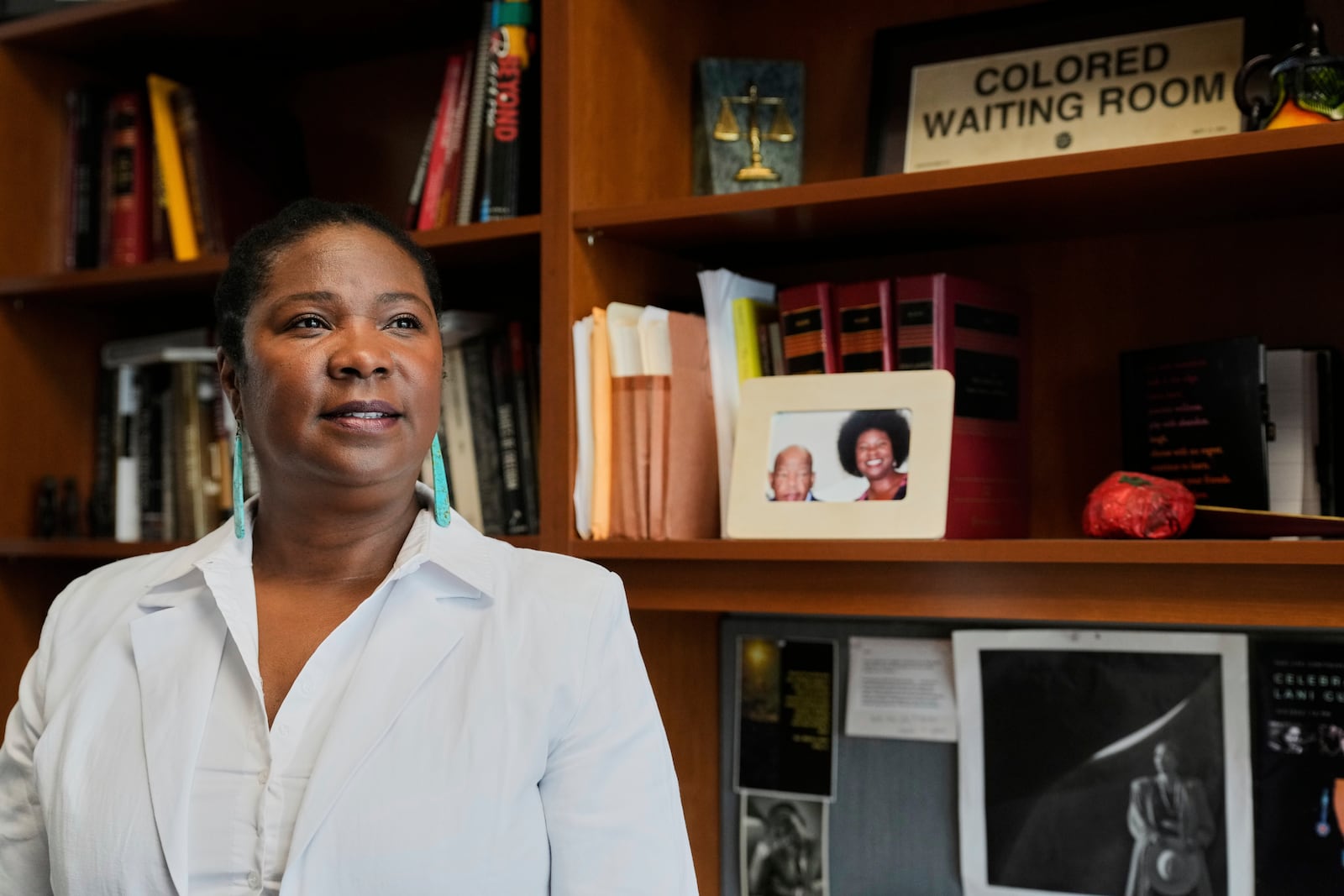 Tanya Washington, a professor of law at Georgia State University, poses for a portrait in her office near a framed photo of her wearing her hair in an afro, Tuesday, May 6, 2025, in Atlanta. (AP Photo/Stephanie Scarbrough)