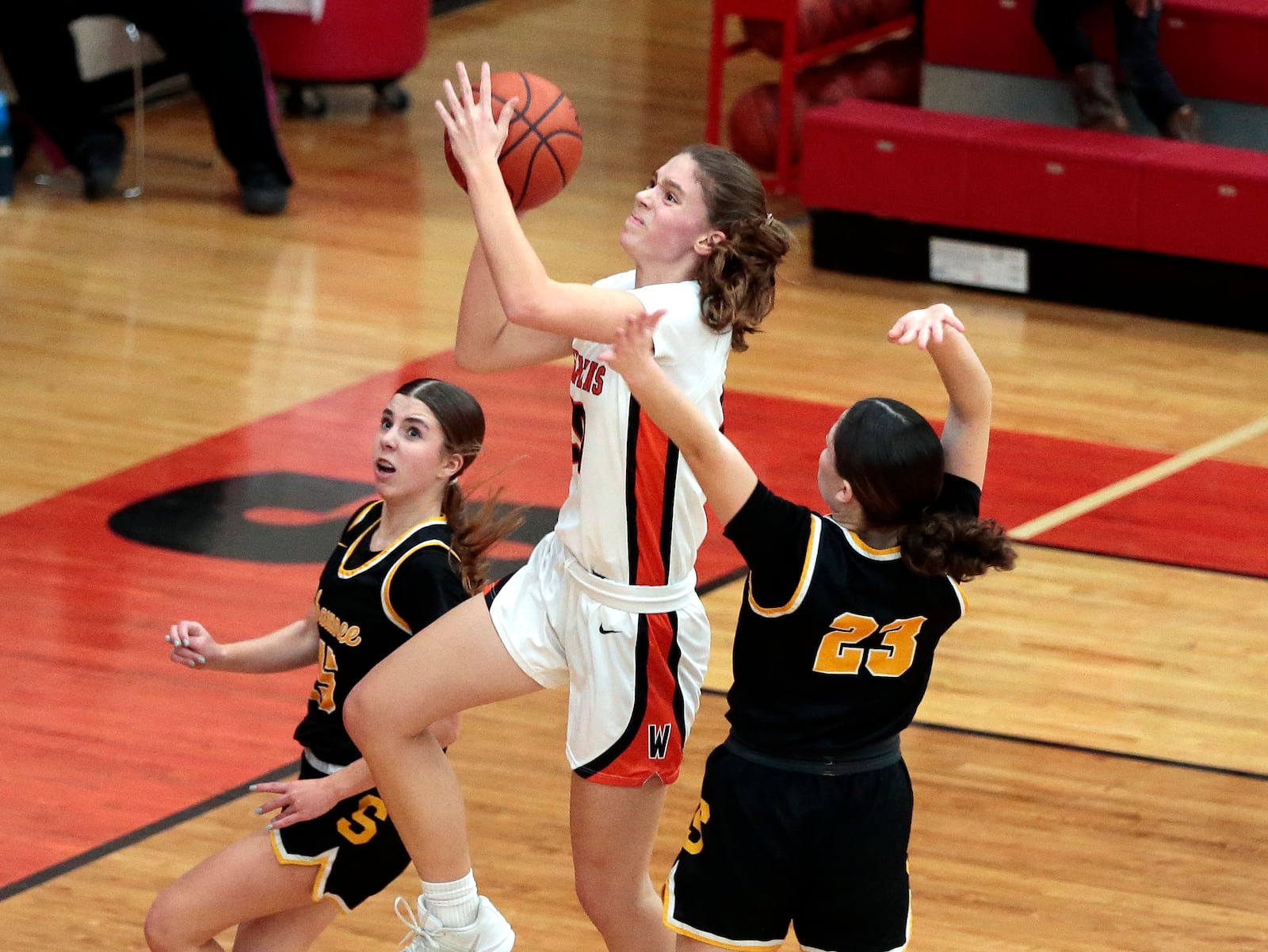 Waynesville senior Maddie Kolaczkowski drives for a layup between Shawnee freshman Hadley Mattern (left) and sophomore Addie Garberich during their game on Wednesday, Feb. 18, 2026 at Trotwood Madison High School. STEVEN WRIGHT / STAFF