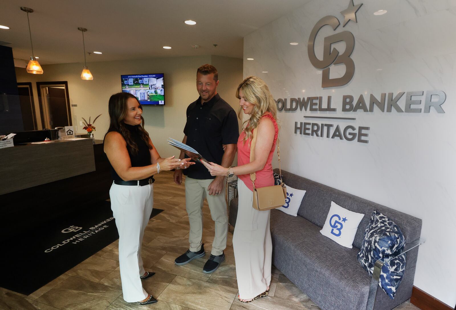 Coldwell Banker Heritage realtor, Amy Braswell talks with Matt and Brynn Coy Friday, Aug. 9, 2024 at her office in Centerville. A lawsuit settlement agreement involving the National Association of REALTORS contains two industry requirements that go into effect Saturday, affecting buyers and sellers of residential properties. MARSHALL GORBY/STAFF