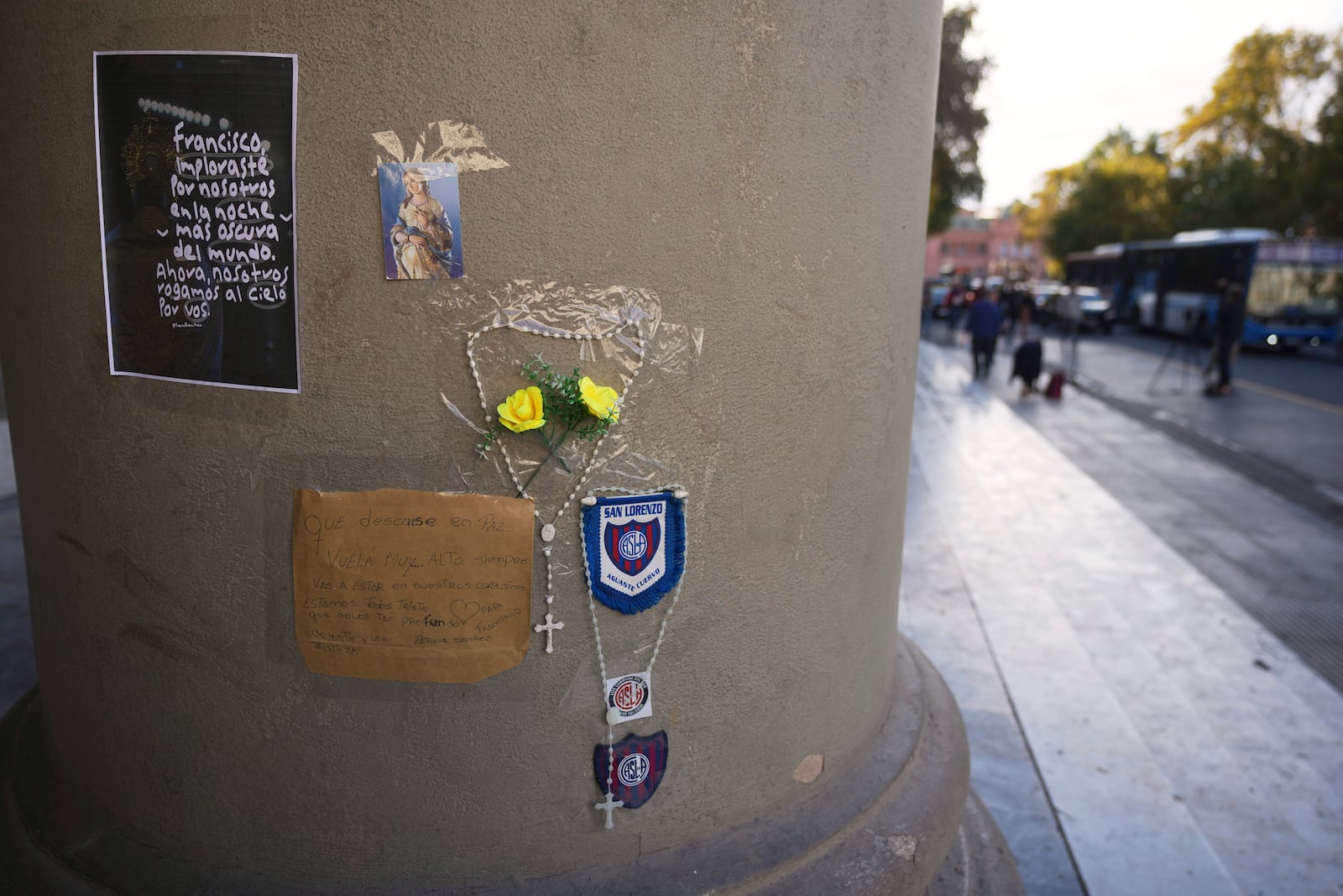 A rosary, messages, and emblems of the San Lorenzo soccer club, of which the late Pope Francis was a fan, are attached to a column of the Cathedral in Buenos Aires, Argentina, following his passing on Monday, April 21, 2025. (AP Photo/Natacha Pisarenko)