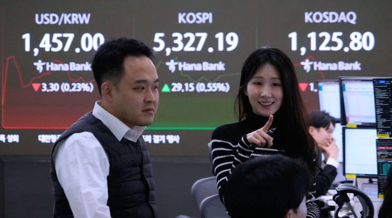 Currency traders work near a screen showing the Korea Composite Stock Price Index (KOSPI), top center, and the foreign exchange rate between U.S. dollar and South Korean won, top left, at the foreign exchange dealing room of the Hana Bank headquarters in Seoul, South Korea, Tuesday, Feb. 10, 2026. (AP Photo/Ahn Young-joon)