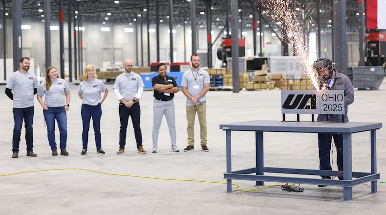 United Alloy worker TJ Pullins cuts through a company on Tuesday as company officials watch during a ceremony at the company's facility off Union Airpark Boulevard. The company hopes to have 400 employees when hiring at the metals fabrication business is finished. BRYANT BILLING / STAFF