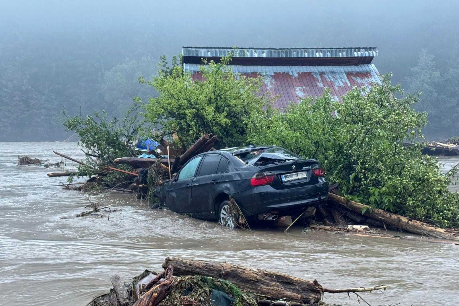 In this image released by the Romanian Emergency Services Suceava (ISU Suceava)a car and house are damaged after a flash flood in the village of Brosteni, northern Romania, Monday, July 28, 2025. (Romanian Emergency Services - ISU Suceava via AP)