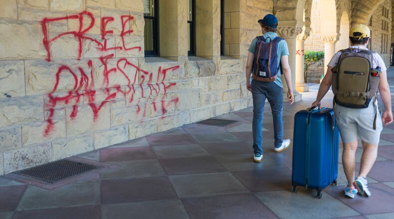 FILE - Students walk by graffiti near university president Richard Saller's office at Stanford University in Palo Alto, Calif., June 5, 2024. (AP Photo/Nic Coury, File)