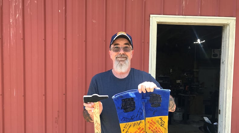 Bill Pyles stands outside of his forging workshop with the hammer and gloves he used on the show. His wife and children signed the hammer and gloves with encouraging messages. ALICE MOMANY/STAFF