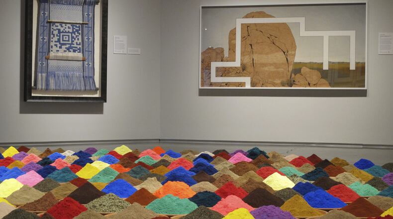 In this Aug. 30, 2017 photo, Bolivian artist Sonia Falcone's "Campo de Color (Color Field)" is displayed in the foreground at the exhibit, ''Unsettled,'' on display into January at the Nevada Museum of Art in Reno, Nev. It consists of 88 terracotta bowls filled with bright, multicolored pigments and a variety of ground spices, including pepper, clove, cumin, mustard, curry, cinnamon and nutmeg. (AP Photo/Scott Sonner)