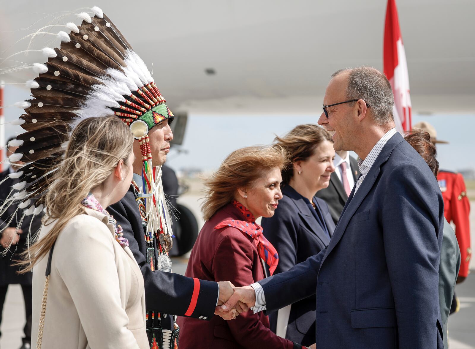 German Chancellor Friedrich Merz, right, is greeted by Steven Crowchild, second left, of the Tsuut'ina First Nation, as he arrives in Calgary, Alberta, Sunday, June 15, 2025, to attend the G7 Leaders meeting taking place in Kananaskis. (Jeff McIntosh/The Canadian Press via AP)