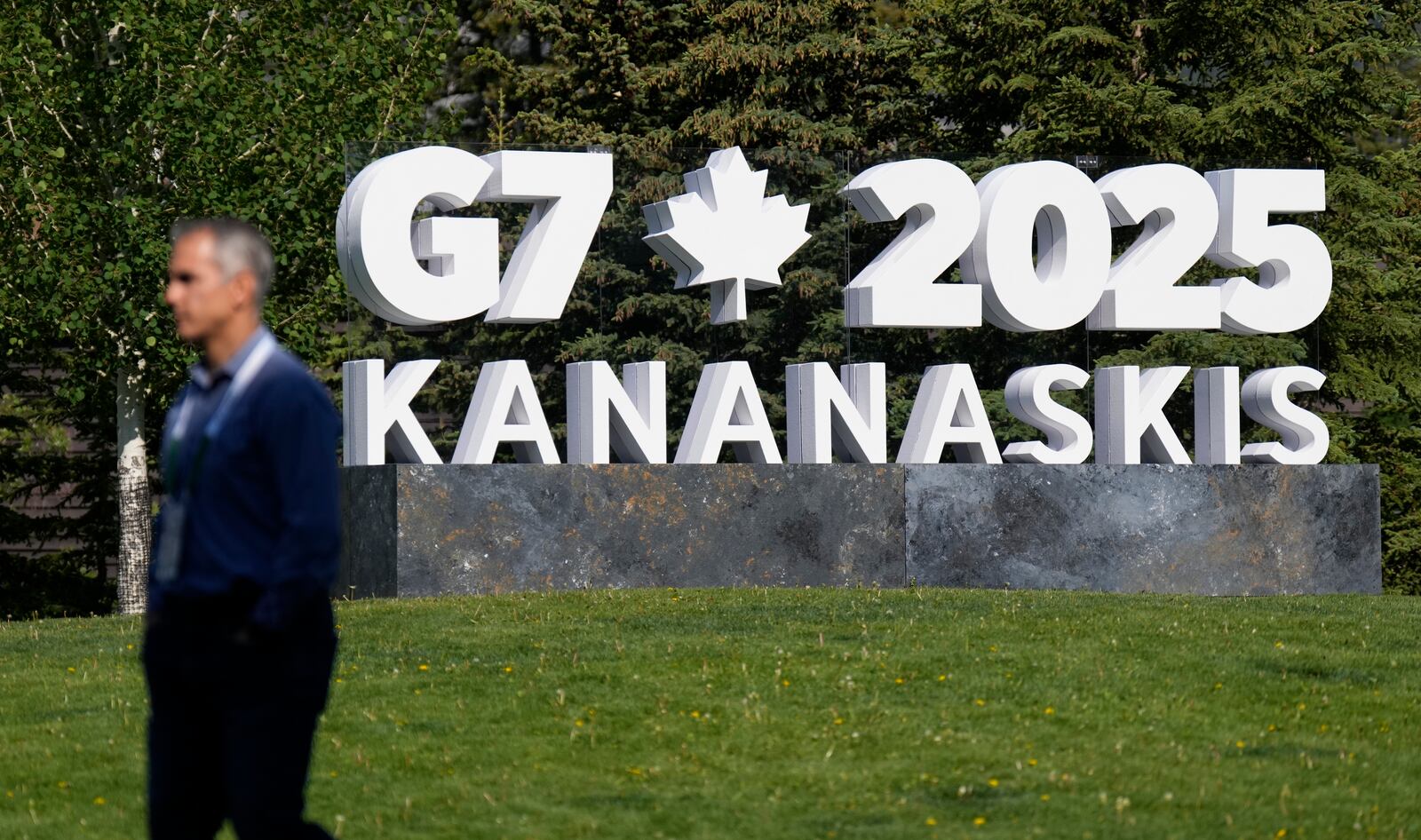 A man walks past a G7 sign outside the media centre for the G7 Summit on Sunday, June 15, 2025 in Banff, Alberta. (Adrian Wyld/The Canadian Press via AP)
