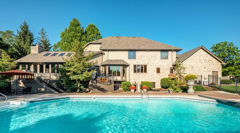 Recreational amenities abound at the back of the home with an in-ground swimming pool with a paver walk-around, a partially enclosed fire pit with built-in seating and a lighted tennis court with a side viewing area installed with wood bleachers.