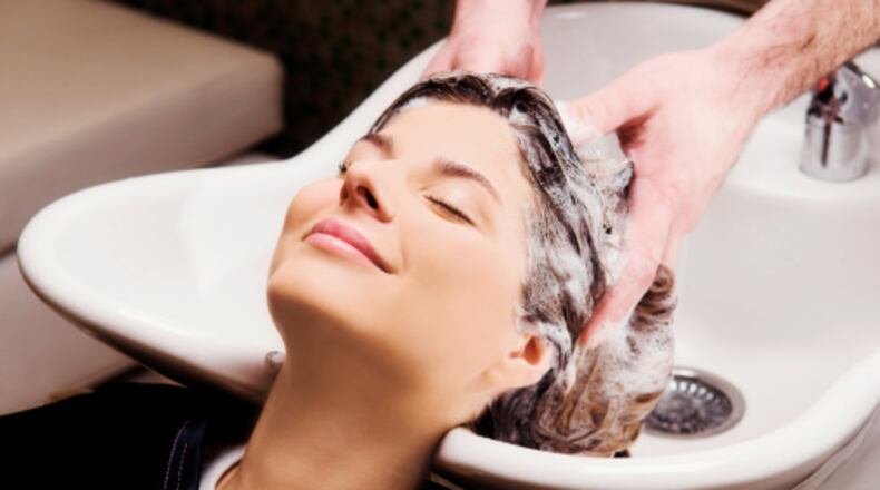 Young woman getting hair shampooed at salon