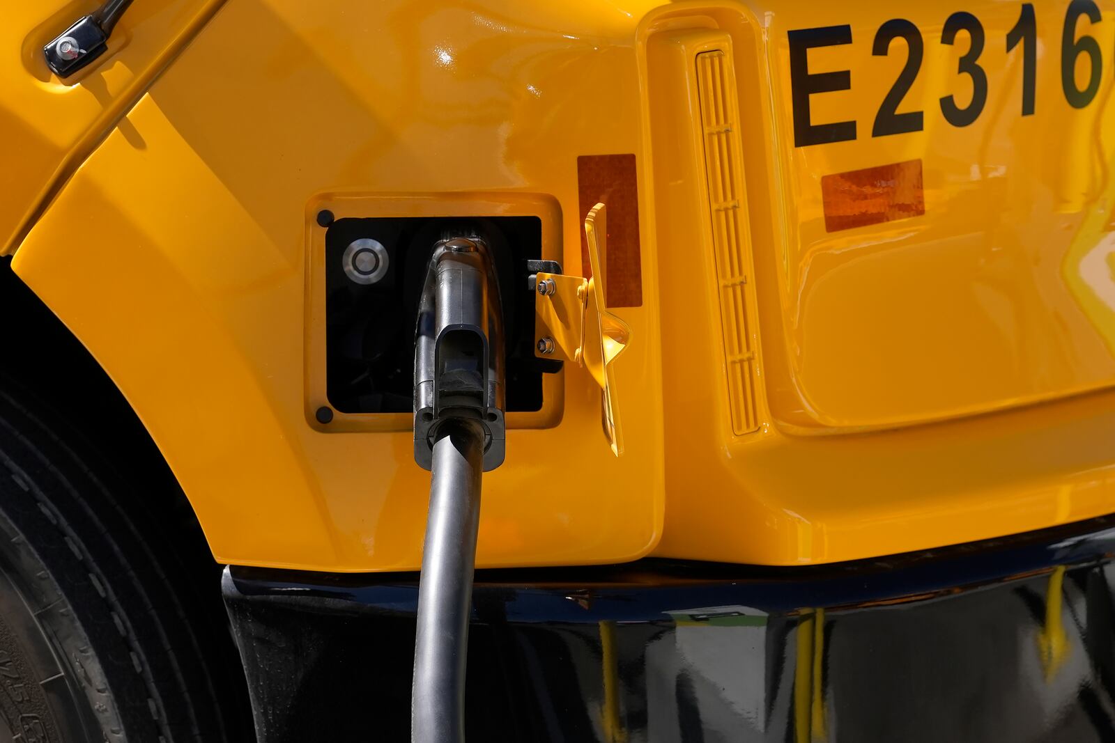 FILE - A Zum electric bus is plugged into charging a station before a news conference announcing the Oakland Unified School District as being the first major school district in the country to use 100% electric school buses at the Zum/OUSD bus yard in Oakland, Calif., on Aug. 27, 2024. (AP Photo/Jeff Chiu, File)