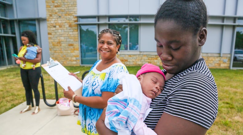 Tiara Thomas holds her baby So-Nae Turner as Natalie Jones, a certified community health worker from Butler County Moms and Babies First, looks on during a PRIM Community Action Team event outside Primary Health Solutions Health Center in Middletown, Tuesday, Aug. 29, 2017. Th PRIM team - consisting of local community leaders, Pastors, advocates and concerned citizens are working together to combat Infant Mortality. GREG LYNCH / STAFF