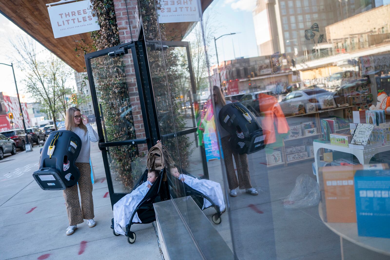Elizabeth Mahon, owner of the baby store Three Littles, holds the door open for a customer who purchased a car seat ahead of tarriff-driven price increases, at the Union Market location in Washington, on Wednesday, April 16, 2025. (AP Photo/Nathan Howard)