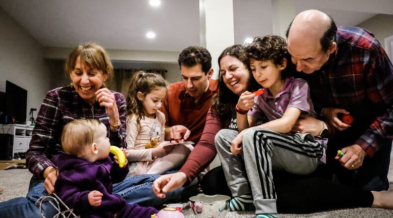 Mike and Marcie Sherman, center in the back, are a military family. They have decided to remain in Dayton. Marcie's parents, Julie and Philip Goldstein, on the far left and right, moved to Dayton during the pandemic. The children, from left, Eillen, Darah and Bernard Sherman. JIM NOELKER/STAFF