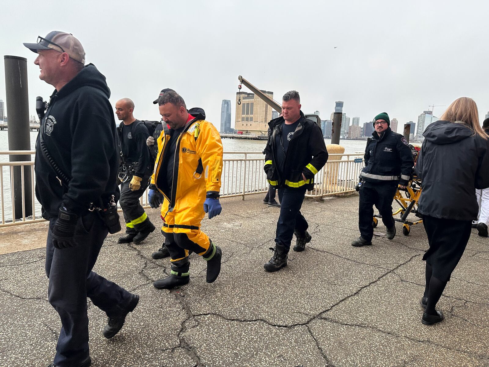 First responders walk along Pier 40, Thursday, April 10, 2025, in New York, across from where a helicopter went down in the Hudson River in Jersey City, N.J. (AP Photo/Jennifer Peltz)