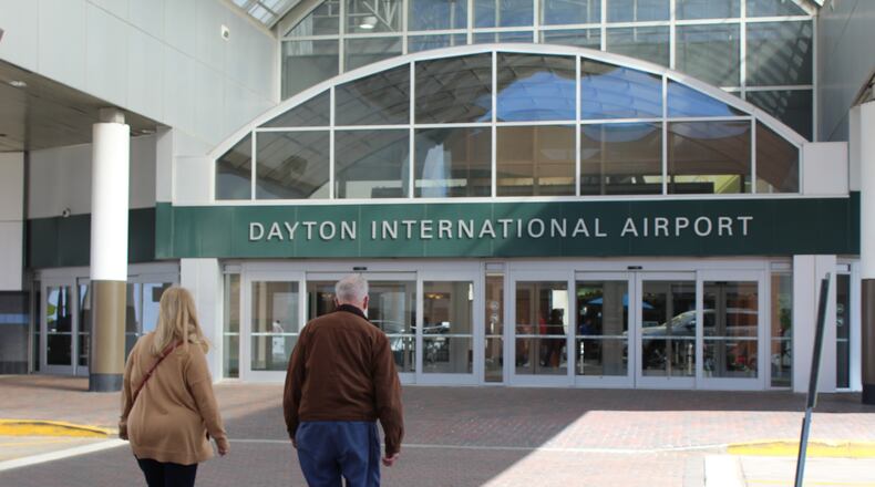 Travelers walk in front of the Dayton International Airport. CORY FROLIK/STAFF