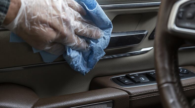 In this undated photo from Edmunds, common touch points are wiped down in the interior of a vehicle, which is one way to reduce the risk of spreading the coronavirus inside the cabin. Apply disinfectant using wipes or spray disinfectant onto a soft cloth, and use disposable gloves to protect your hands. (Scott Jacobs/Edmunds via AP)
