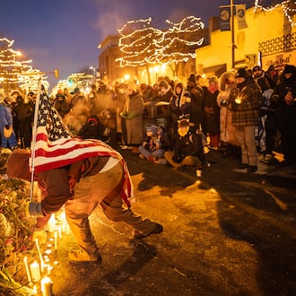 A man carrying an American flag visits a makeshift memorial at the site where Alex Pretti was shot and killed by ICE agents on Saturday, in Minneapolis, on Saturday, Jan. 24, 2026. People who knew Pretti, an intensive-care nurse at a Veterans Affairs hospital, pushed back against what they called a smear campaign by federal officials. “He was a good man,” his family said. (David Guttenfelder/The New York Times)