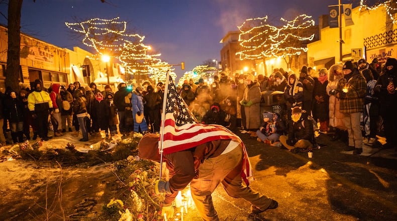 A man carrying an American flag visits a makeshift memorial at the site where Alex Pretti was shot and killed by ICE agents on Saturday, in Minneapolis, on Saturday, Jan. 24, 2026. People who knew Pretti, an intensive-care nurse at a Veterans Affairs hospital, pushed back against what they called a smear campaign by federal officials. “He was a good man,” his family said. (David Guttenfelder/The New York Times)