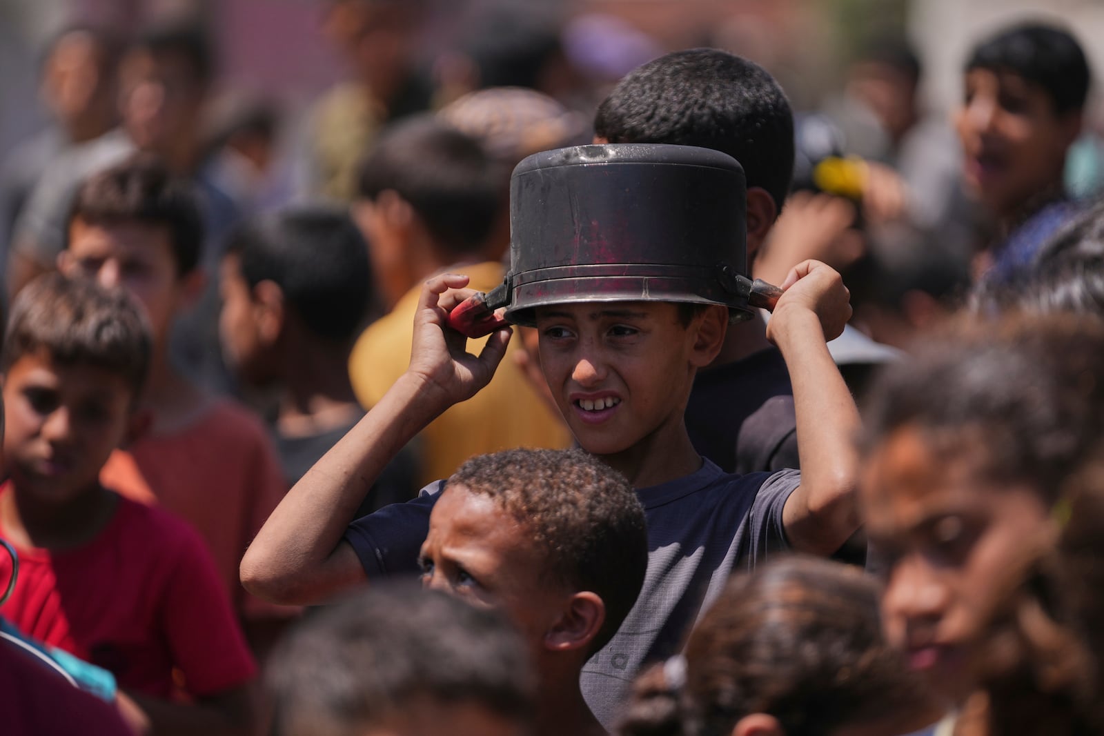A young Palestinian waits to collect donated food at a food distribution kitchen in Deir al-Balah, Gaza Strip, Friday, May 30, 2025. (AP Photo/Abdel Kareem Hana)
