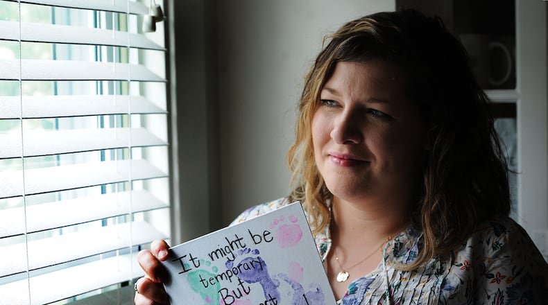 Bethany Sibbitt, a Montgomery County foster caregiver, holds a painting that features the tiny footprints of the infant in her care. MARSHALL GORBY\STAFF