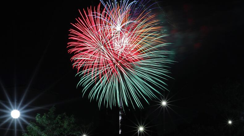 People gathered in every parking lot around downtown Springfield to watch the inaugural Buck Creek Boom fireworks show on the banks of Buck Creek Saturday night. BILL LACKEY/STAFF