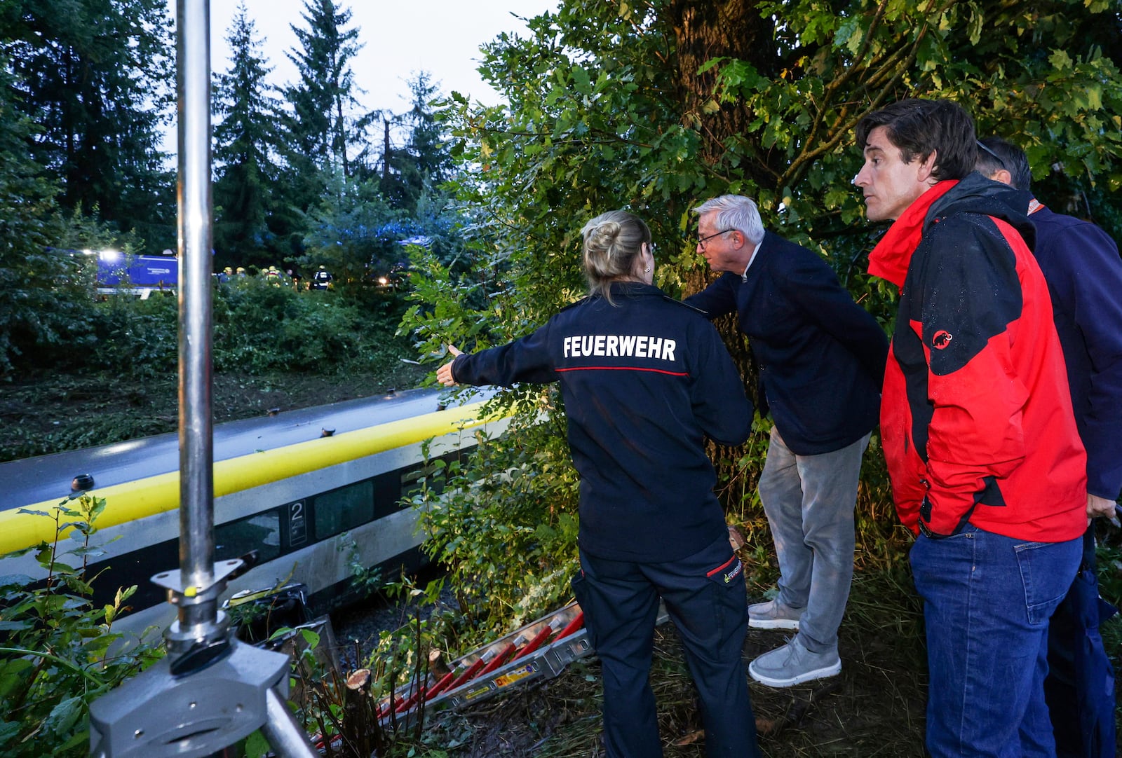 District fire chief of the Biberach district, Charlotte Ziller, left, shows the district administrator of the Biberach district, Mario Glaser, and Interior Minister Thomas Strobel, center, the scene of the derailed regional passenger train accident near Riedlingen, Germany, Sunday, July 27, 2025. (Thomas Warnack/dpa via AP)