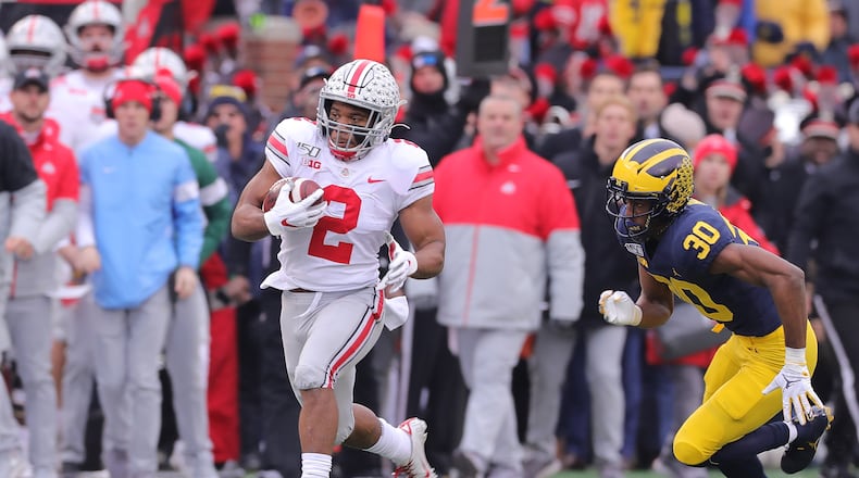 ANN ARBOR, MI - NOVEMBER 30: J.K. Dobbins #2 of the Ohio State Buckeyes runs for a first down during as Daxton Hill #30 of the Michigan Wolverines gives chase during the first quarter of the game at Michigan Stadium on November 30, 2019 in Ann Arbor, Michigan. (Photo by Leon Halip/Getty Images)