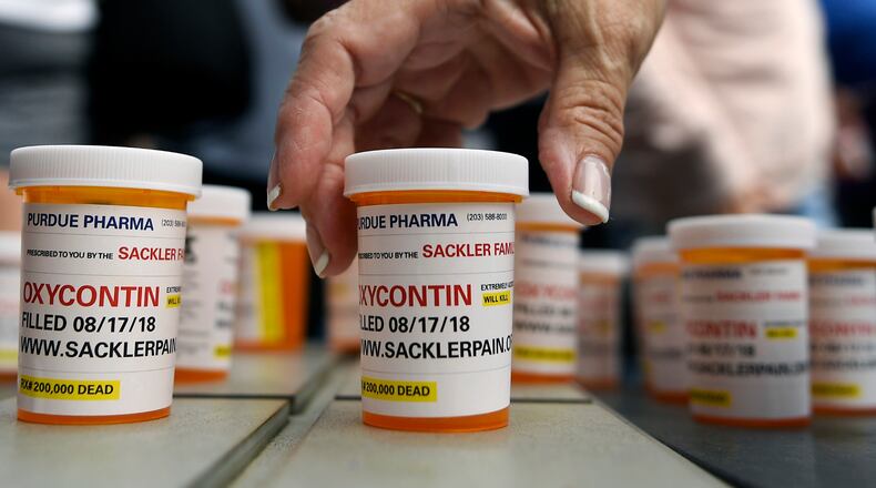 FILE - In this Aug. 17, 2018, file photo, family and friends who have lost loved ones to OxyContin and opioid overdoses leave pill bottles in protest outside the headquarters of Purdue Pharma in Stamford, Conn. A lawyer for the company, which is facing lawsuits over its marketing of the powerful painkiller OxyContin in driving the opioid epidemic, says states would get more money from settling rather than continuing their lawsuits against the Purdue Pharma and the Sackler family who own it. (AP Photo/Jessica Hill, File)