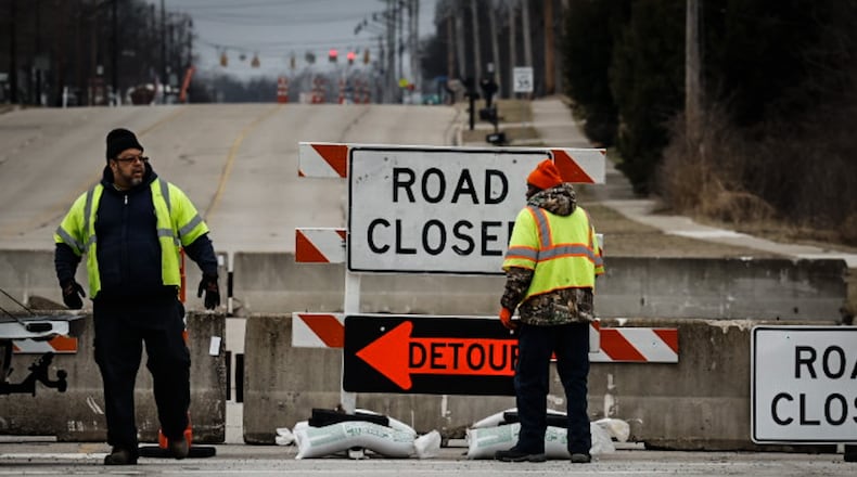 Workers set more sandbags on the road closed signs at Ohio 49 and East Main Street Friday February 10, 2023. The bridge over Dry Run is going to be repaired because of erosion. JIM NOELKER/STAFF