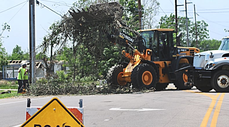Public works workers continue to clean up tornado debris on Benchwood Road in Butler Twp. where a car reportedly hit a worker after crashing though the road closed sign. (Marshall Gorby/Staff)