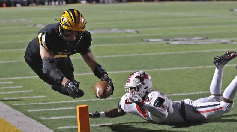 Centerville's Nic Bruder holds the ball out to cross the goal line as he knocked out of bounds by Wayne's Darrius Pope during Friday's game. Bruder scored a touchdown on the play. BILL LACKEY/STAFF