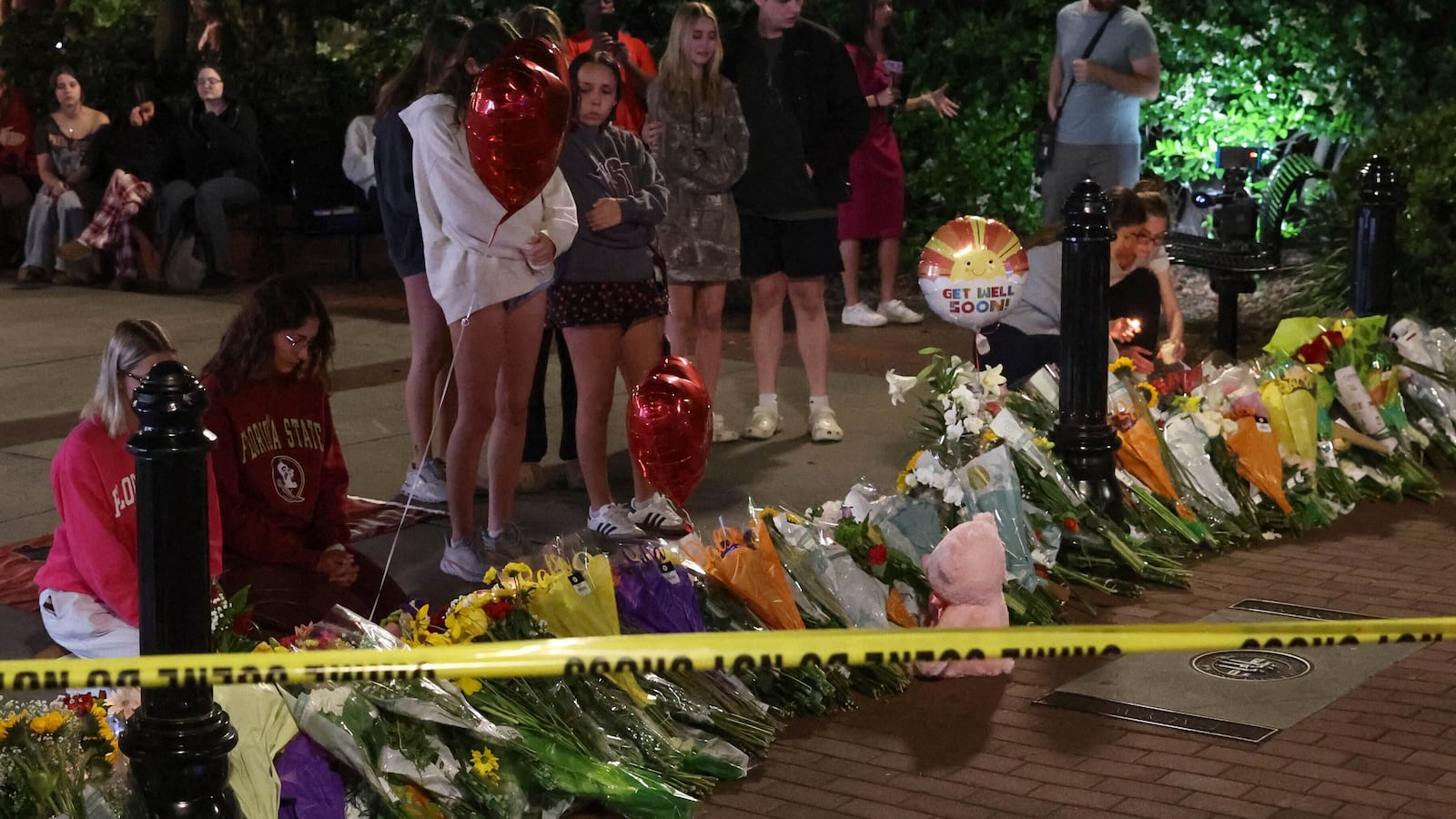 An impromptu memorial shared online brings students bearing flowers into the evening near the center of the Florida State campus in sight of the Student Union building, Tallahassee, Fla., Thursday, April 17, 2025. (AP Photo/Gary McCullough)