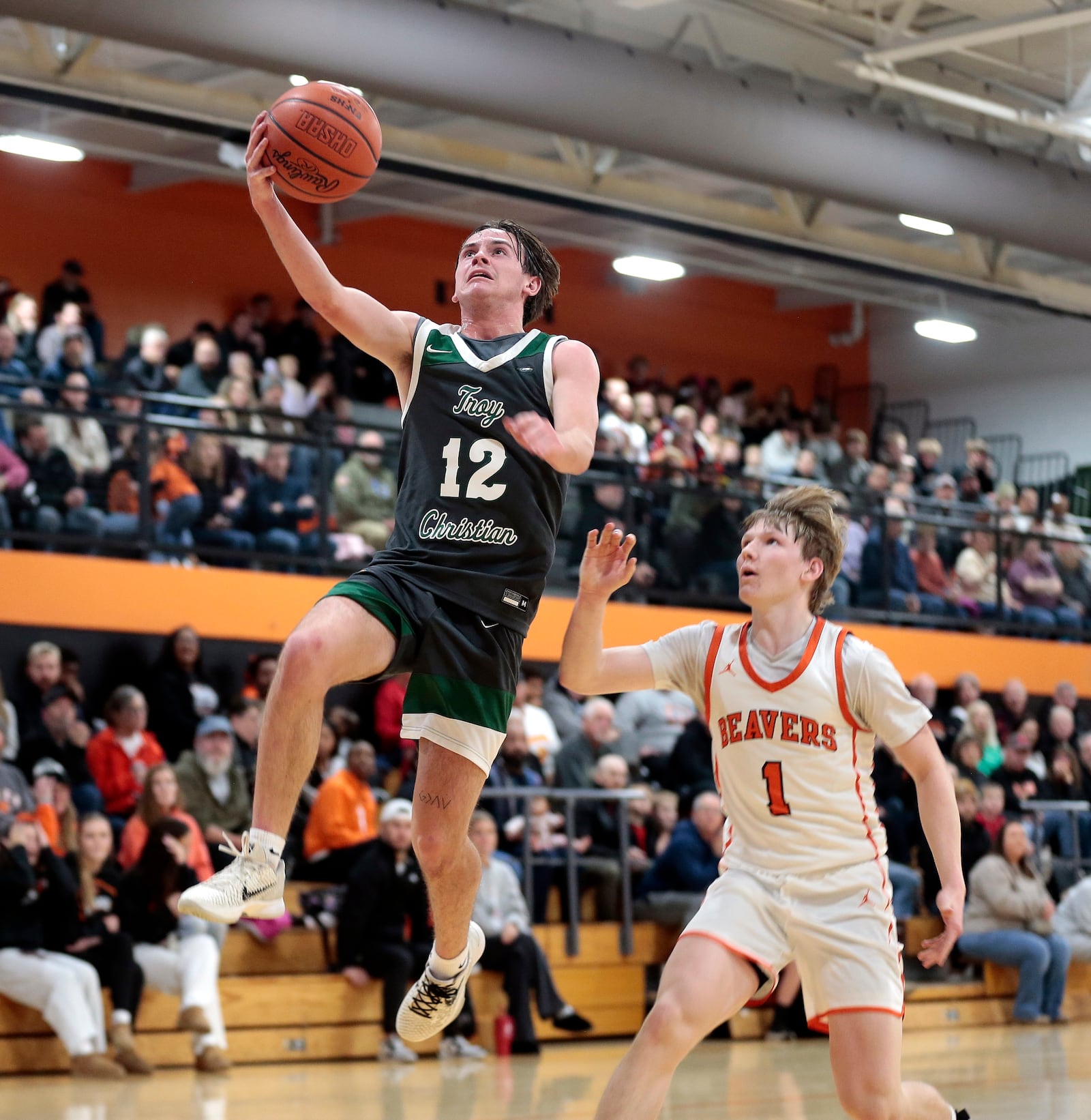 Troy Christian senior Brennan Hochwalt (12) drives for a layup past Beavercreek junior Jack Haskins (1) during a 54-53 win at Beavercreek in non-league play Tue., Dec. 2, 2025. STEVEN WRIGHT / STAFF