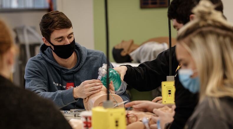 Sinclair College paramedic student Allec Eckert, left, practices intubation on a pediatric dummy during class Tuesday Nov. 30, 2021. Wright State University and Sinclair Community College gave additional $1,000 scholarships to qualifying students who went straight from high school to college this year. JIM NOELKER/STAFF