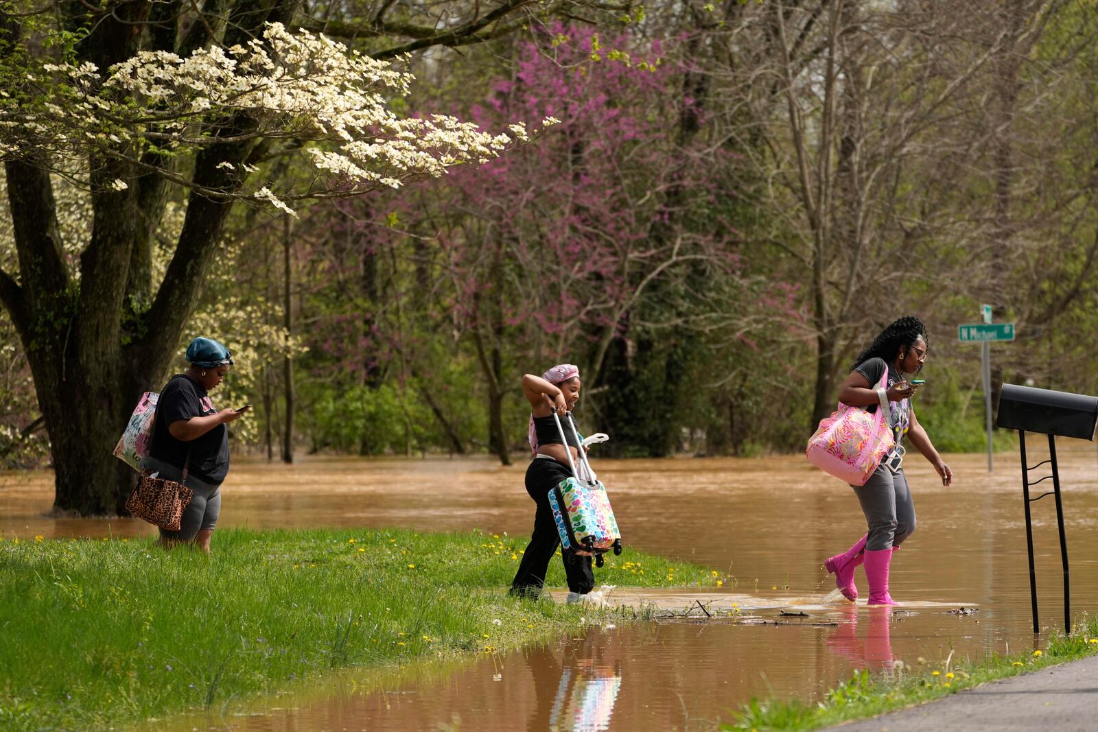 Marquetta Wheeler, right, with Samaria Williams and Jemaria Shaw walk through flood waters as they leave their home on Marietta Drive in Hopkinsville, Ky., Friday, April 4, 2025. (AP Photo/George Walker IV)