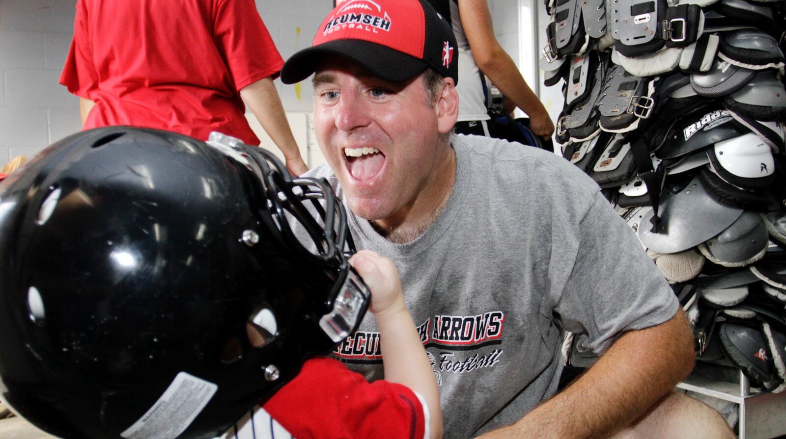 Kent Massie helps his son Dalton try on a helmet during the annual Moms Camp presented by the Tecumseh High School football team on Monday, July 19, 2010. Staff Photo by Barbara J. Perenic