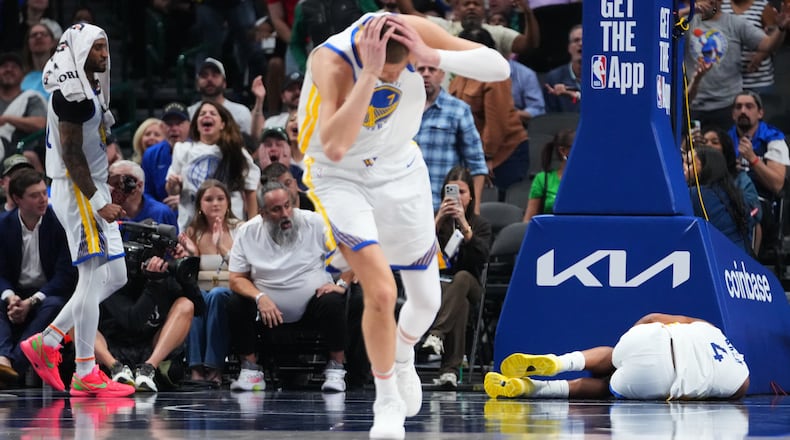Golden State Warriors center Kristaps Porzingis, center, and guard Gary Payton II, left, react after guard Moses Moody (4) suffered an injury during overtime of an NBA basketball game against the Dallas Mavericks Monday, March 23, 2026, in Dallas. (AP Photo/Julio Cortez)