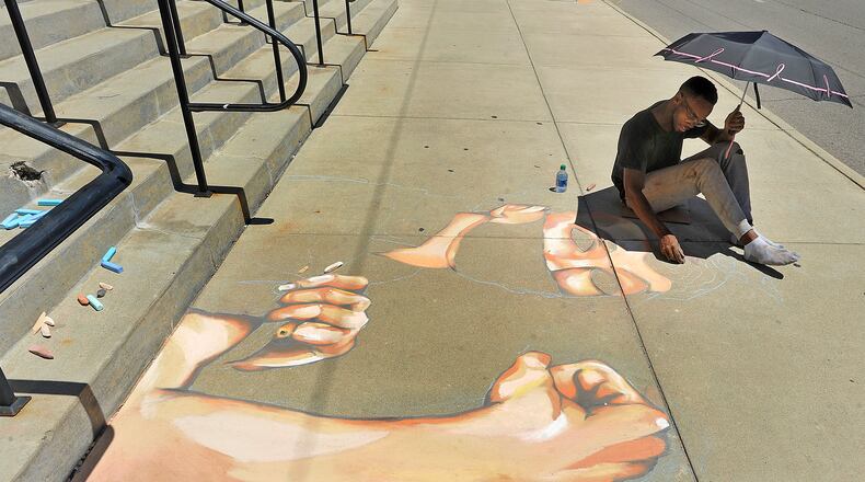 Boy Blue works on a chalk drawing Wednesday in front of City Hall in Dayton. The art work lasts about 24 hours. MARSHALL GORBY\STAFF