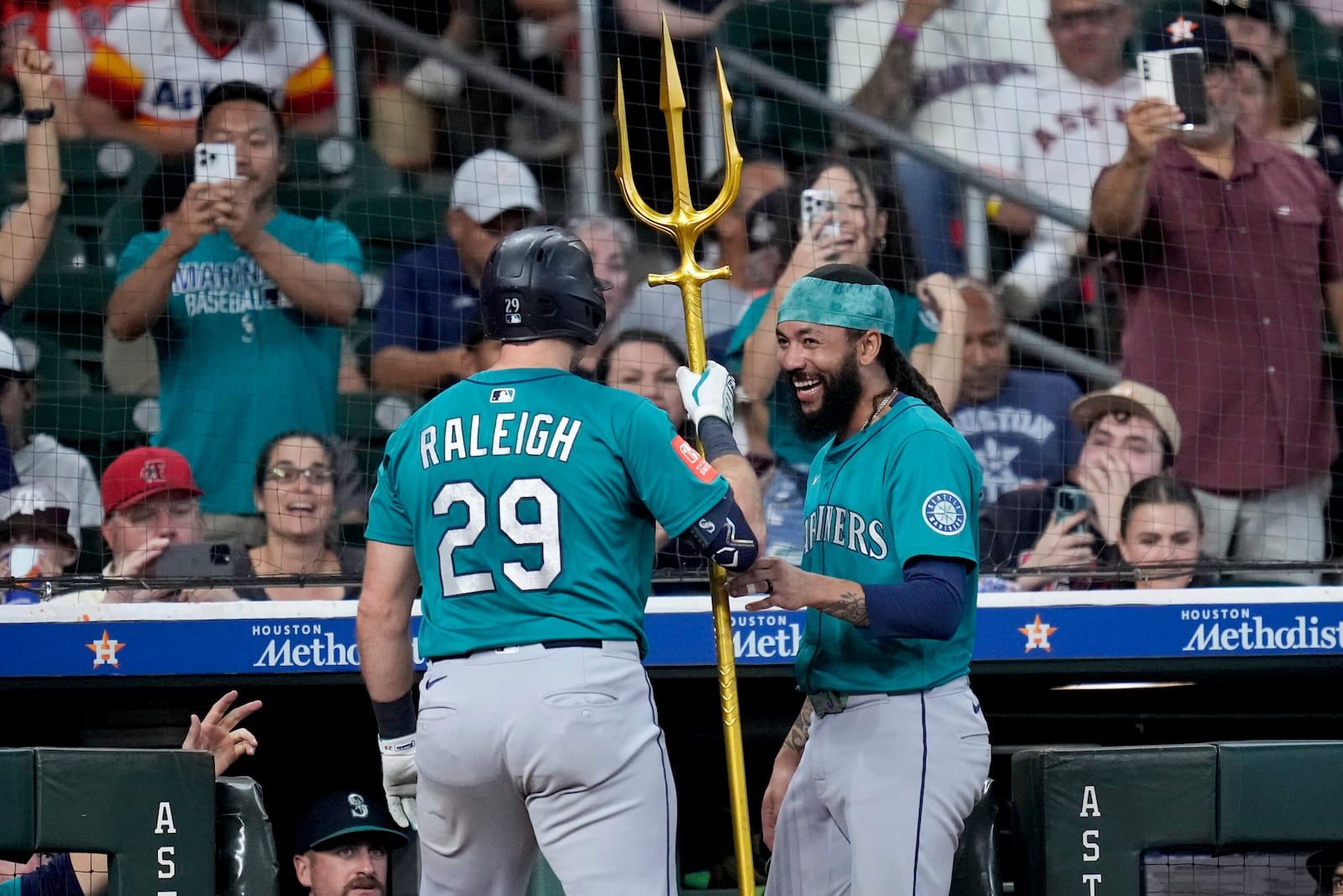 Seattle Mariners' J.P. Crawford, right, presents Cal Raleigh a trident after Raleigh hit a two-run home run against the Houston Astros during the second inning of a baseball game Sunday, Sept. 21, 2025, in Houston. (AP Photo/Eric Christian Smith)