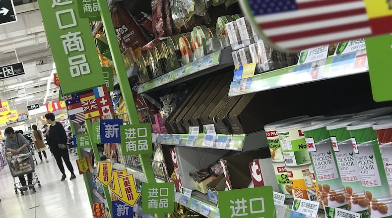 Women push a shopping cart near nuts and sweets imported from the United States and other countries displayed on a section selling imported foods at a supermarket in Beijing, Monday, April 2, 2018. China raised import duties on a $3 billion list of U.S. pork, fruit and other products Monday in an escalating tariff dispute with President Donald Trump that companies worry might depress global commerce. (AP Photo/Andy Wong)