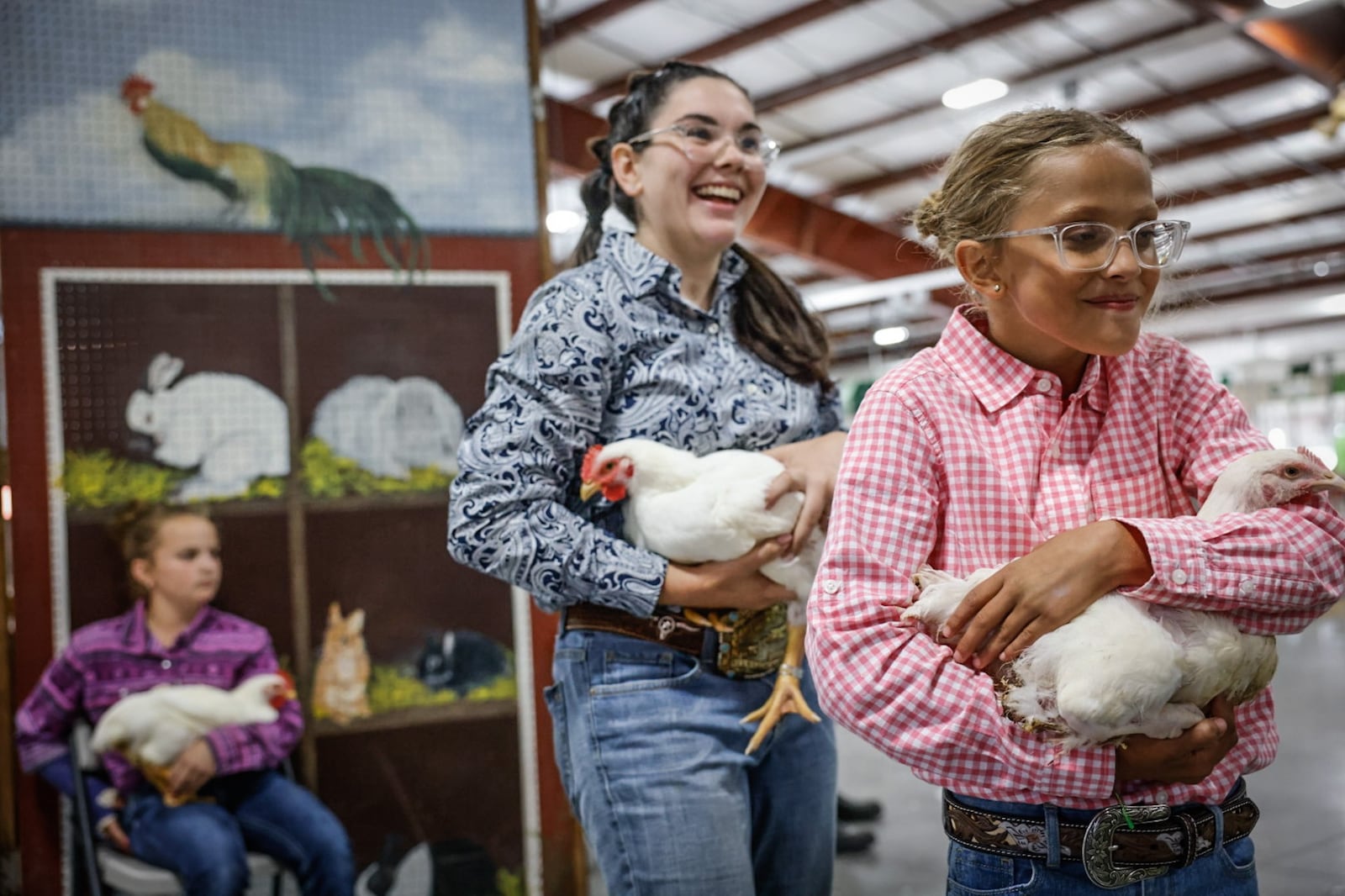 Ashlynn Cummins (left) of Germantown and Ell Grace Rike of Lewisburg head to the stage to auction their meat chickens during the Junior fair sale at the 2024 Montgomery County Fair. Rike made $150 for her meat chicken. JIM NOELKER/STAFF